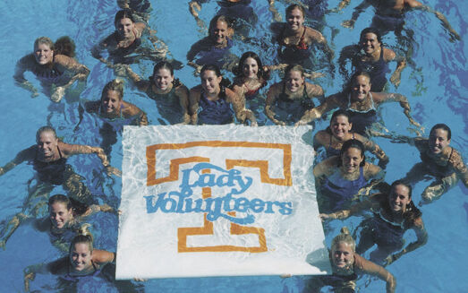Swimmers surround a Lady Vols banner in the pool