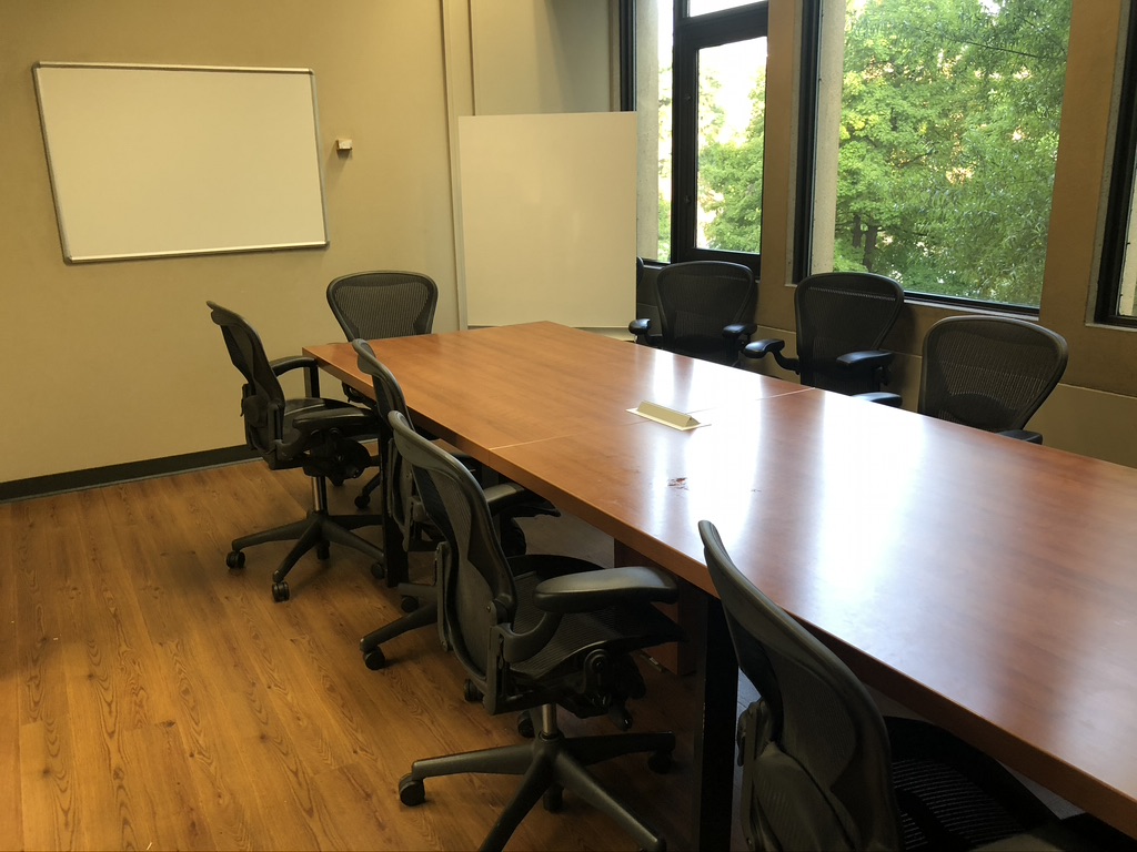 a table and chairs with some white boards in the corner of the room