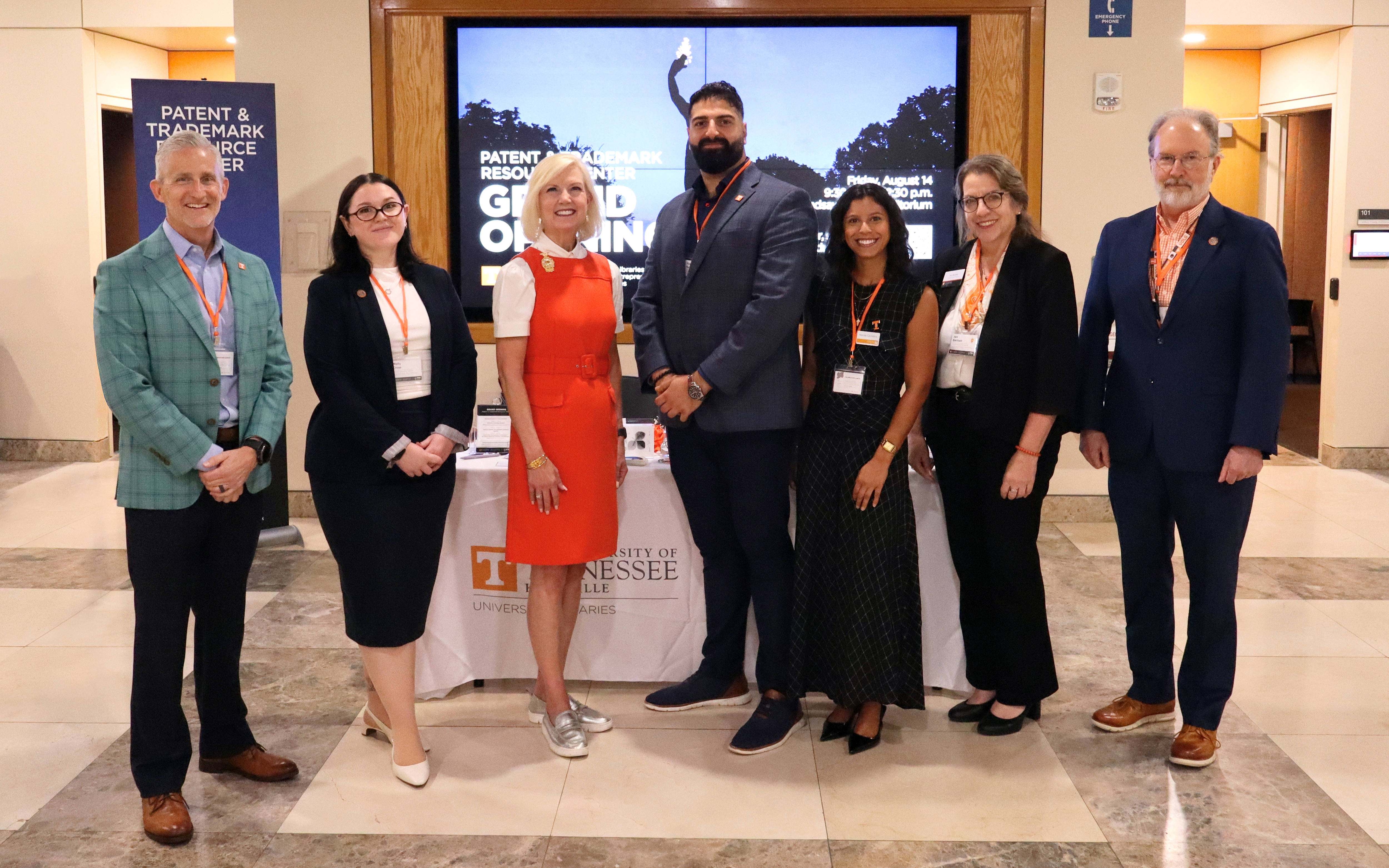Faculty and staff stand in front of graphic display promoting the Grand Opening of the Patent and Trademark Resource Center.