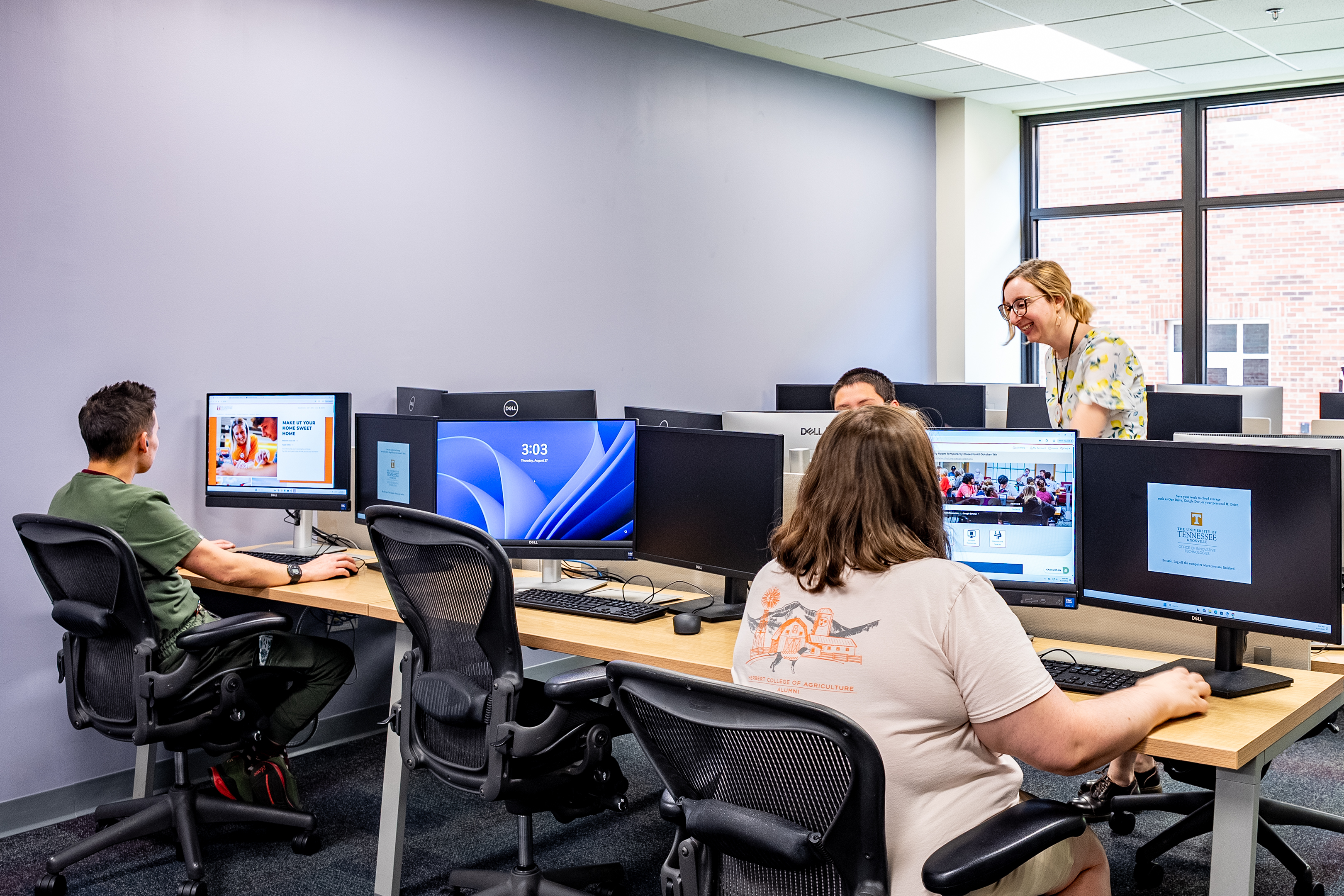 Photograph of three students and a librarian in a computer lap