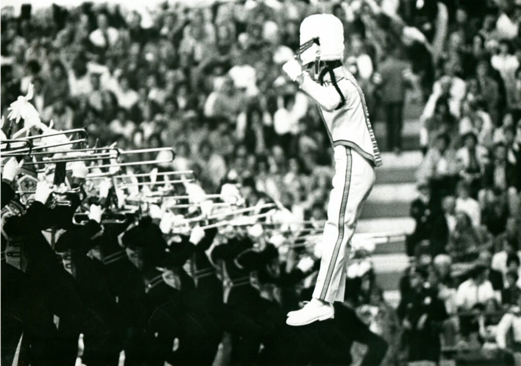 Drum major jumps while conducting in front of trombone line